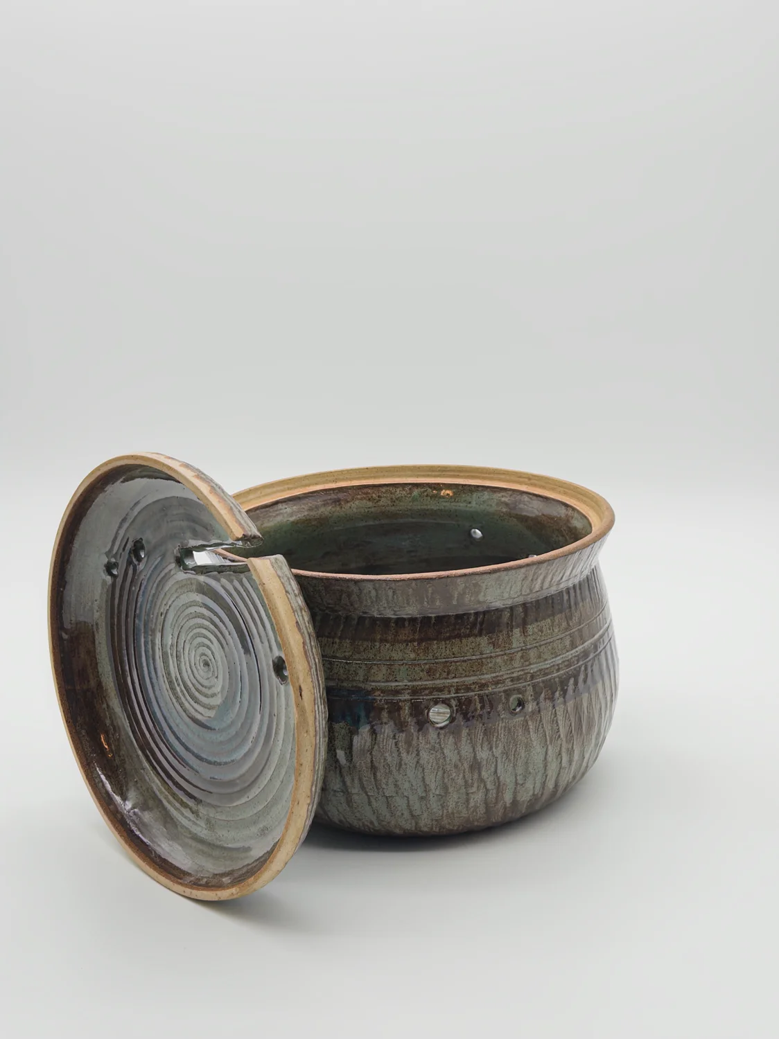 Brown and green lidded pot with small holes and a notch in the lid, view 3