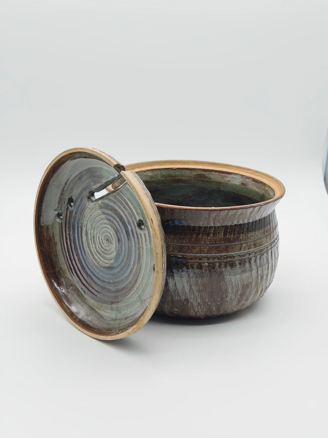 Brown and green lidded pot with small holes and a notch in the lid, view 4