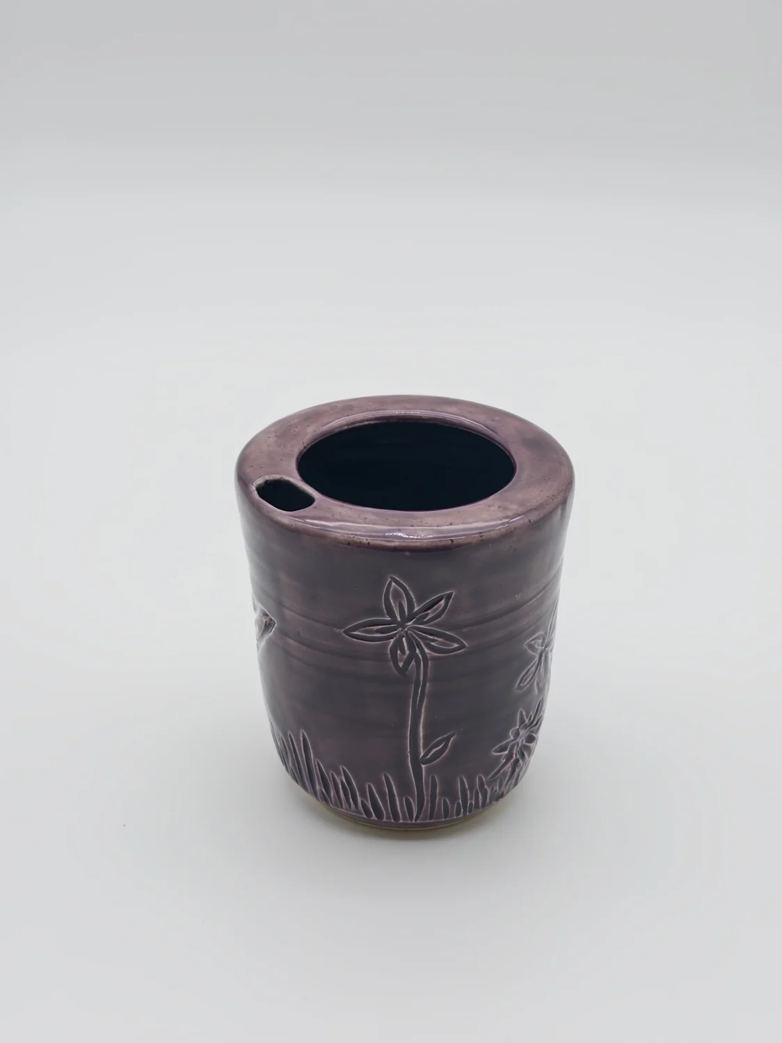 Purple travel cup with carved flowers and a sipping opening